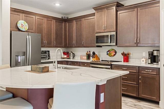 11579 Weaver Hollow Rd, New Port Richey, FL 34654 - kitchen featuring appliances with stainless steel finishes, a sink, light stone counters, a breakfast bar, and a center island with sink