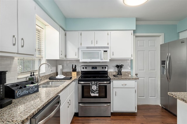 4851 NE 7th St, Ocala, FL 34470 - kitchen featuring stainless steel appliances, a sink, white cabinets, light stone counters, and ornamental molding
