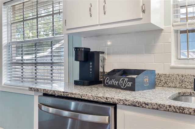4851 NE 7th St, Ocala, FL 34470 - kitchen view of dishwasher, white cabinetry, backsplash, and light stone counters