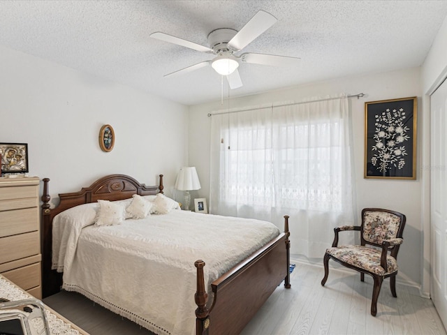 3832 Sailmaker Ln Unit 3832, Holiday, FL 34691 - bedroom featuring a textured ceiling, light wood-style floors, a ceiling fan, and baseboards