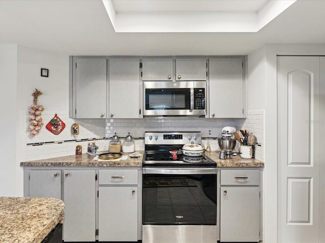 3832 Sailmaker Ln Unit 3832, Holiday, FL 34691 - kitchen featuring appliances with stainless steel finishes, a raised ceiling, backsplash, and light countertops