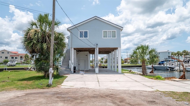 6322 Aureau Ave, Hudson, FL 34667 - back of property with a carport, stairway, concrete driveway, a water view, and a yard