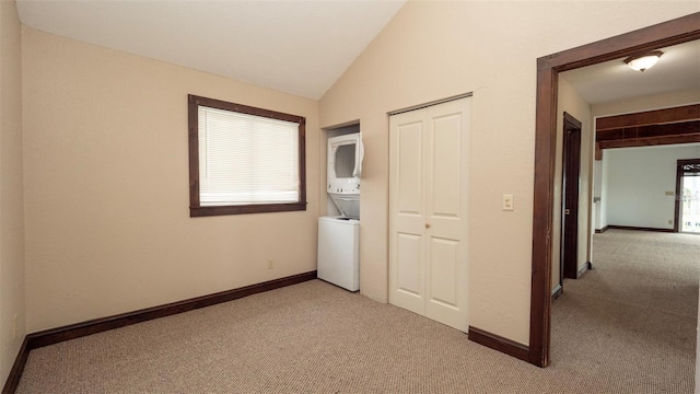 6322 Aureau Ave, Hudson, FL 34667 - unfurnished bedroom featuring stacked washing machine and dryer, light colored carpet, a closet, vaulted ceiling, and baseboards