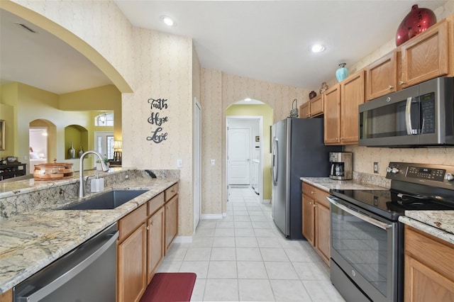 11637 Spindrift Loop, Hudson, FL 34667 - kitchen featuring appliances with stainless steel finishes, wallpapered walls, light tile patterned floors, light stone countertops, and arched walkways