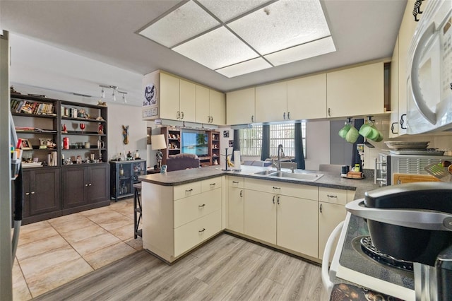 4350 Sawgrass Blvd, New Port Richey, FL 34653 - kitchen with cream cabinets, a sink, a peninsula, light wood-type flooring, and white microwave