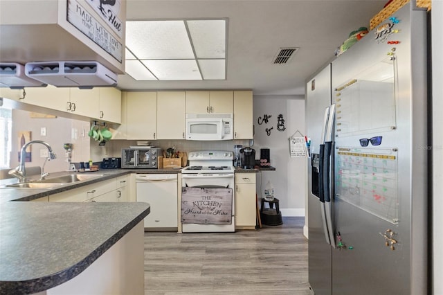 4350 Sawgrass Blvd, New Port Richey, FL 34653 - kitchen with white appliances, a sink, dark countertops, cream cabinetry, and light wood finished floors