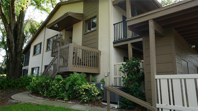 13012 Wedgewood Way Unit A, Hudson, FL 34667 - view of property exterior featuring stucco siding, stairway, and central AC unit