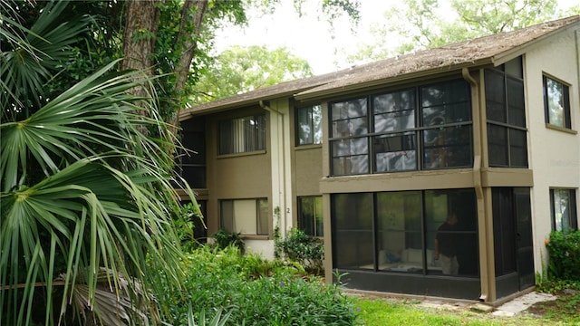 13012 Wedgewood Way Unit A, Hudson, FL 34667 - rear view of house featuring stucco siding and a sunroom