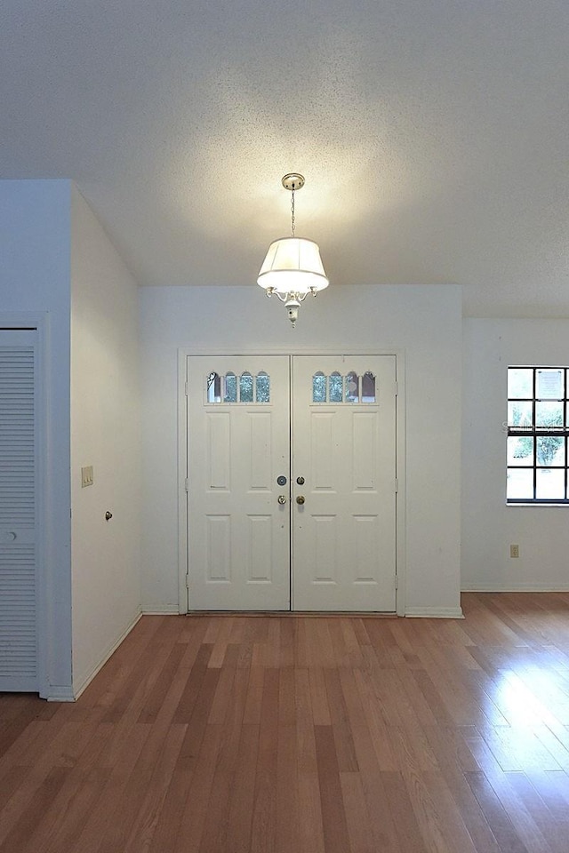 11364 Orangewood Ct, Spring Hill, FL 34609 - entryway featuring light wood-style floors, baseboards, a textured ceiling, and a chandelier