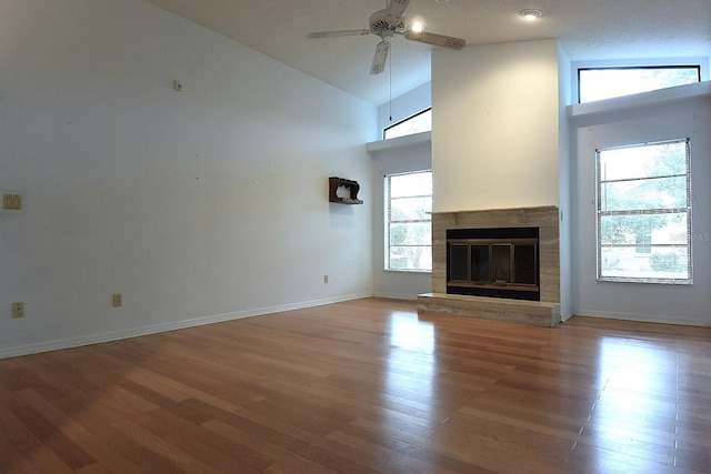 11364 Orangewood Ct, Spring Hill, FL 34609 - unfurnished living room with a ceiling fan, a glass covered fireplace, light wood finished floors, baseboards, and high vaulted ceiling
