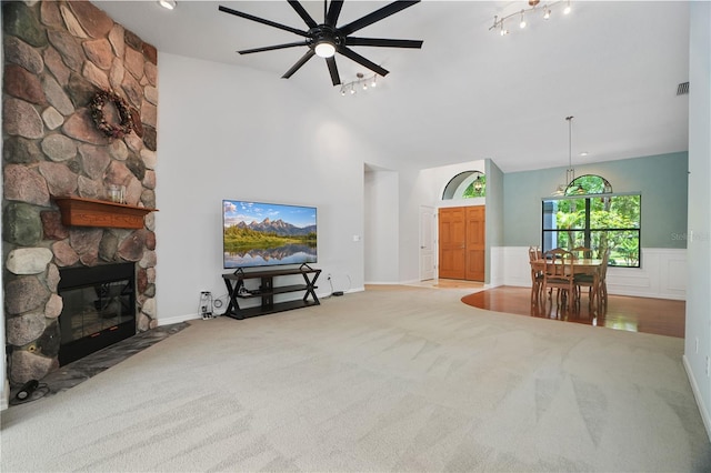 8518 Quail Hollow Blvd, Wesley Chapel, FL 33544 - carpeted living area featuring a ceiling fan, a stone fireplace, high vaulted ceiling, and a wainscoted wall