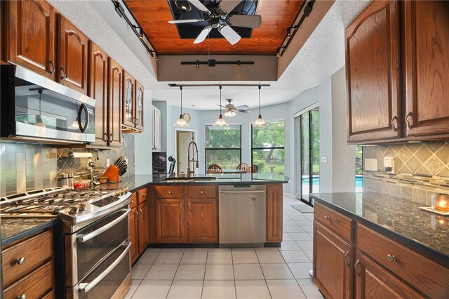 8518 Quail Hollow Blvd, Wesley Chapel, FL 33544 - kitchen with appliances with stainless steel finishes, ceiling fan, a peninsula, a sink, and decorative backsplash