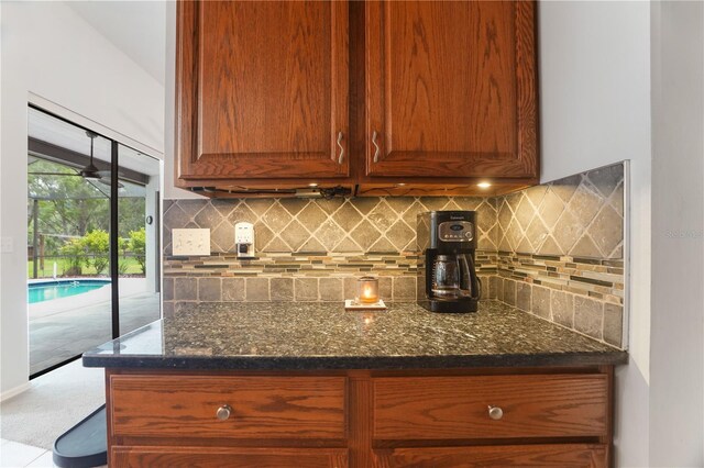 8518 Quail Hollow Blvd, Wesley Chapel, FL 33544 - kitchen featuring dark stone countertops, decorative backsplash, and brown cabinetry