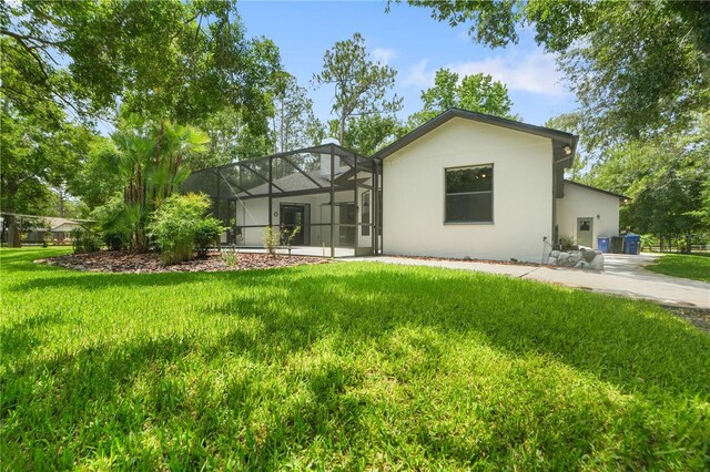 8518 Quail Hollow Blvd, Wesley Chapel, FL 33544 - rear view of house with stucco siding, a yard, and glass enclosure