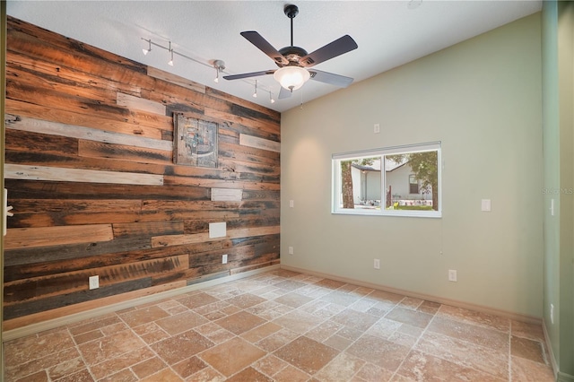 8518 Quail Hollow Blvd, Wesley Chapel, FL 33544 - empty room with wooden walls, stone tile flooring, rail lighting, ceiling fan, and baseboards