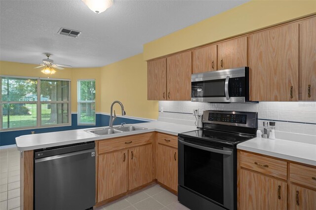 35046 Smoketree Ln, Dade City, FL 33523 - kitchen with stainless steel appliances, a peninsula, light countertops, decorative backsplash, and a textured ceiling