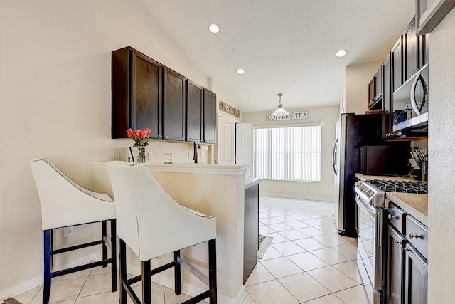 8335 Crescent Moon Dr, New Port Richey, FL 34655 - kitchen featuring stainless steel appliances, light countertops, a kitchen bar, a peninsula, and light tile patterned floors