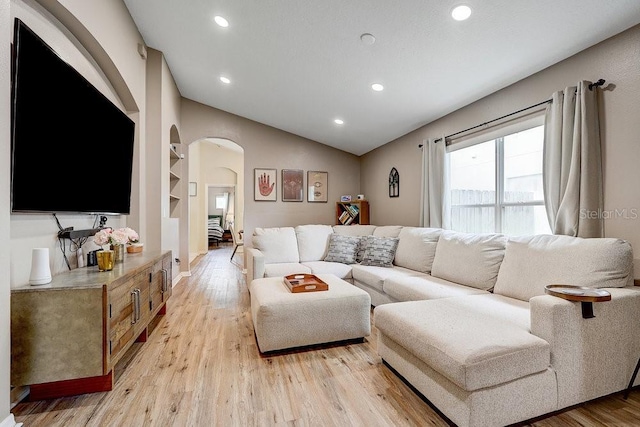 8335 Crescent Moon Dr, New Port Richey, FL 34655 - living room featuring arched walkways, light wood-style floors, recessed lighting, and lofted ceiling