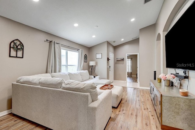 8335 Crescent Moon Dr, New Port Richey, FL 34655 - living room featuring arched walkways, light wood-style flooring, lofted ceiling, baseboards, and recessed lighting
