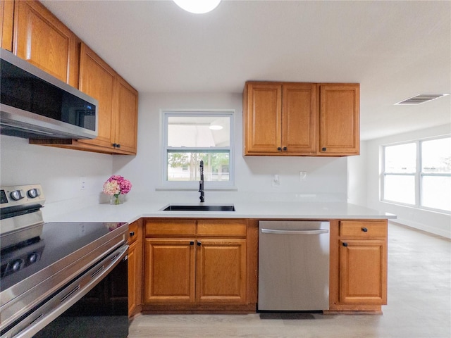 7608 Bougenville Dr, Port Richey, FL 34668 - kitchen with appliances with stainless steel finishes, a sink, healthy amount of natural light, and brown cabinets