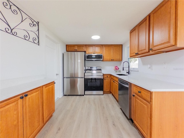 7608 Bougenville Dr, Port Richey, FL 34668 - kitchen featuring stainless steel appliances, a sink, light wood-style floors, light countertops, and brown cabinets