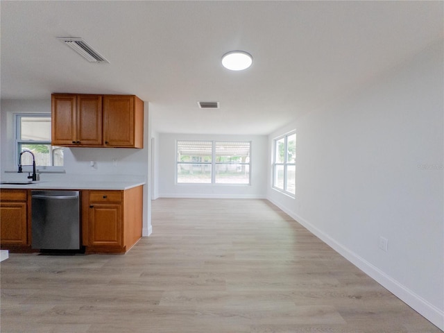 7608 Bougenville Dr, Port Richey, FL 34668 - kitchen with dishwasher, brown cabinetry, a sink, light countertops, and light wood-style flooring