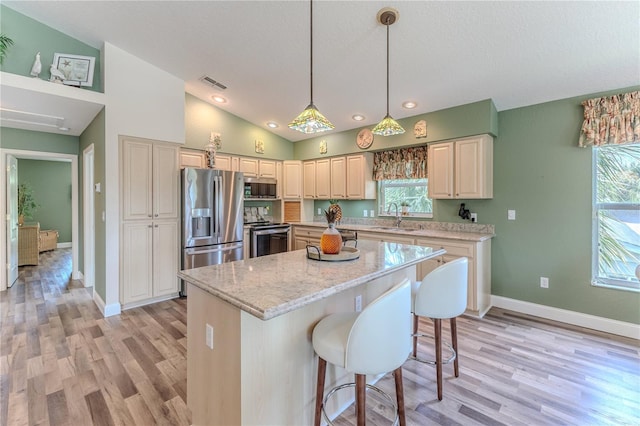 4460 Flounder Dr, Hernando Beach, FL 34607 - kitchen with stainless steel appliances, light wood finished floors, lofted ceiling, a center island, and light stone countertops
