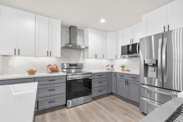 12064 Cradock St, Spring Hill, FL 34608 - kitchen featuring appliances with stainless steel finishes, wall chimney exhaust hood, gray cabinetry, light countertops, and light wood-style flooring