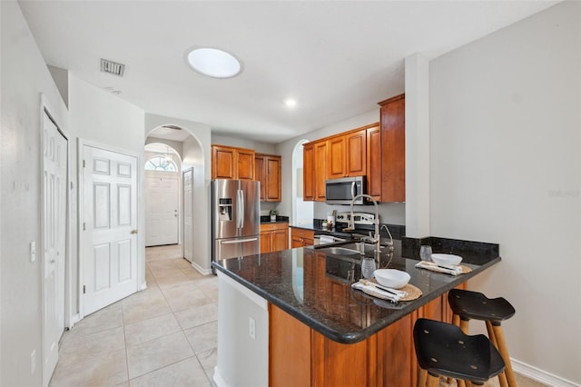 1623 Crossvine Ct, New Port Richey, FL 34655 - kitchen with appliances with stainless steel finishes, arched walkways, a peninsula, brown cabinets, and a sink