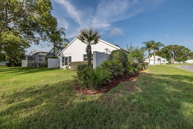 1084 Vista Fina Ct, Spring Hill, FL 34608 - view of side of home featuring stucco siding, a lawn, and glass enclosure