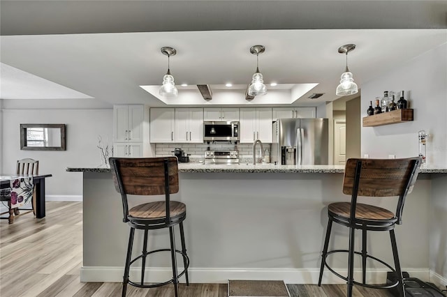 4072 Everett Ave, Spring Hill, FL 34609 - kitchen featuring appliances with stainless steel finishes, a raised ceiling, baseboards, light stone counters, and recessed lighting