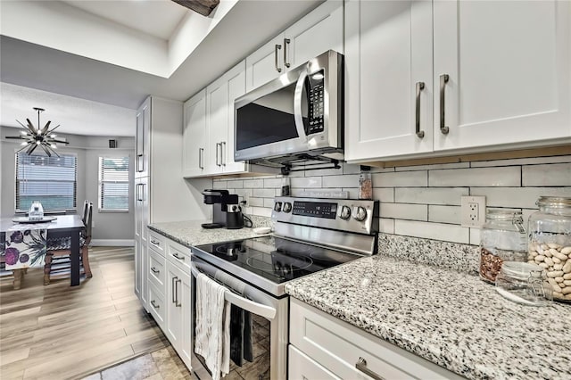 4072 Everett Ave, Spring Hill, FL 34609 - kitchen with appliances with stainless steel finishes, a chandelier, white cabinetry, and light stone counters