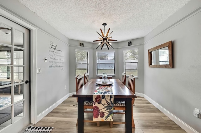 4072 Everett Ave, Spring Hill, FL 34609 - dining room with a chandelier, a textured ceiling, light wood-type flooring, and baseboards