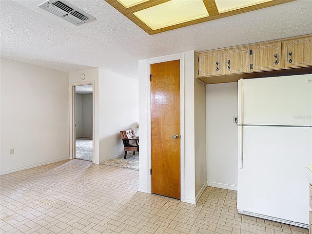10139 Carrin Rd, Spring Hill, FL 34608 - kitchen with freestanding refrigerator, brick patterned flooring, baseboards, and a textured ceiling