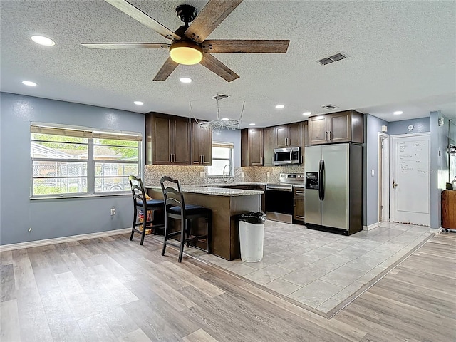11340 Corinthian St, Spring Hill, FL 34609 - kitchen featuring appliances with stainless steel finishes, dark brown cabinets, ceiling fan, a peninsula, and a textured ceiling