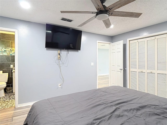 11340 Corinthian St, Spring Hill, FL 34609 - bedroom with light wood finished floors, a closet, a textured ceiling, ensuite bathroom, and ceiling fan