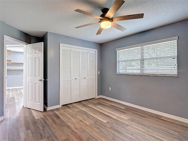 11340 Corinthian St, Spring Hill, FL 34609 - unfurnished bedroom with wood finished floors, a closet, baseboards, a textured ceiling, and a ceiling fan