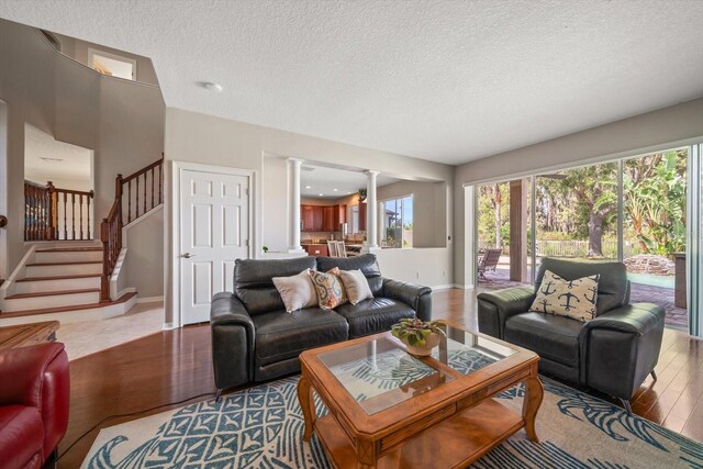17905 Machair Ln, Land O Lakes, FL 34638 - living area featuring decorative columns, wood finished floors, a textured ceiling, baseboards, and stairs