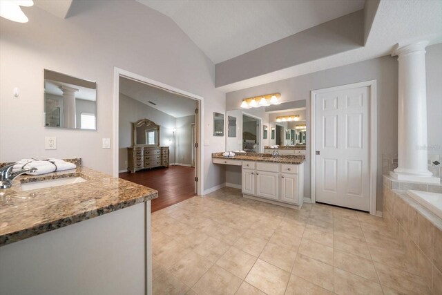 17905 Machair Ln, Land O Lakes, FL 34638 - full bathroom with ornate columns, vaulted ceiling, two vanities, a garden tub, and tile patterned flooring