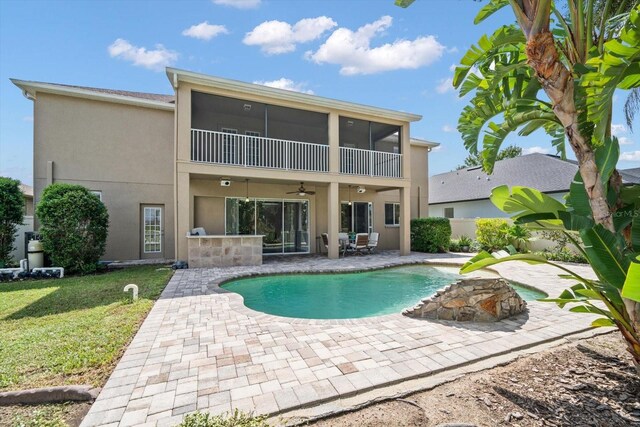 17905 Machair Ln, Land O Lakes, FL 34638 - back of house with ceiling fan, stucco siding, a patio, a sunroom, and a lawn