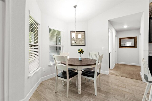 11042 Heth Ct, Weeki Wachee, FL 34613 - dining room with a chandelier, light wood-type flooring, and baseboards