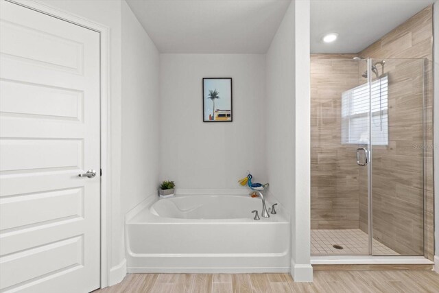 11042 Heth Ct, Weeki Wachee, FL 34613 - full bath featuring a garden tub, a stall shower, and wood finished floors