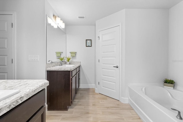 11042 Heth Ct, Weeki Wachee, FL 34613 - full bathroom featuring two vanities, a bath, wood finished floors, and baseboards