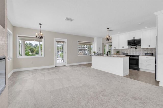 5440 Manatee Point Dr, New Port Richey, FL 34652 - kitchen with a chandelier, black range oven, light carpet, white cabinets, and recessed lighting