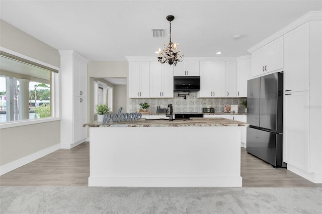 5440 Manatee Point Dr, New Port Richey, FL 34652 - kitchen with freestanding refrigerator, white cabinets, tasteful backsplash, light wood-style floors, and recessed lighting