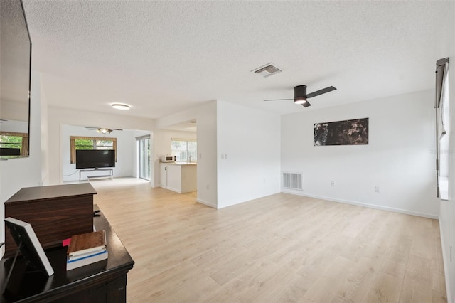 13001 Sawmill Way, Hudson, FL 34667 - unfurnished living room with a ceiling fan, a textured ceiling, light wood-type flooring, and baseboards