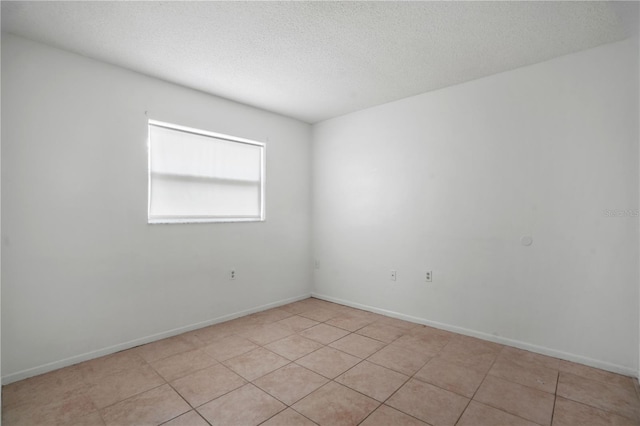 8053 Dedham Dr, Port Richey, FL 34668 - spare room featuring a textured ceiling, light tile patterned flooring, and baseboards