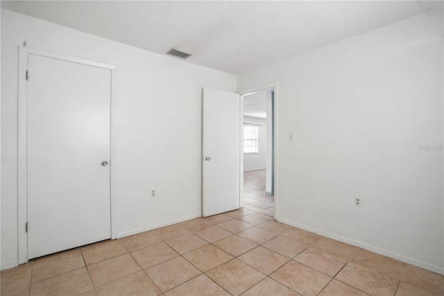 8053 Dedham Dr, Port Richey, FL 34668 - unfurnished bedroom featuring light tile patterned floors, a textured ceiling, and baseboards