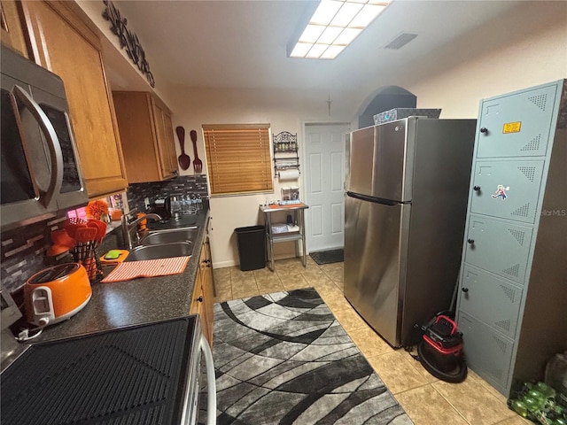 717 Whiteway Dr, Brooksville, FL 34601 - kitchen featuring stainless steel appliances, light tile patterned floors, a sink, and brown cabinetry