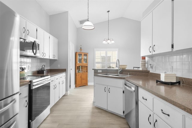 7923 Woburn St, New Port Richey, FL 34653 - kitchen with stainless steel appliances, a sink, a chandelier, white cabinets, and high vaulted ceiling